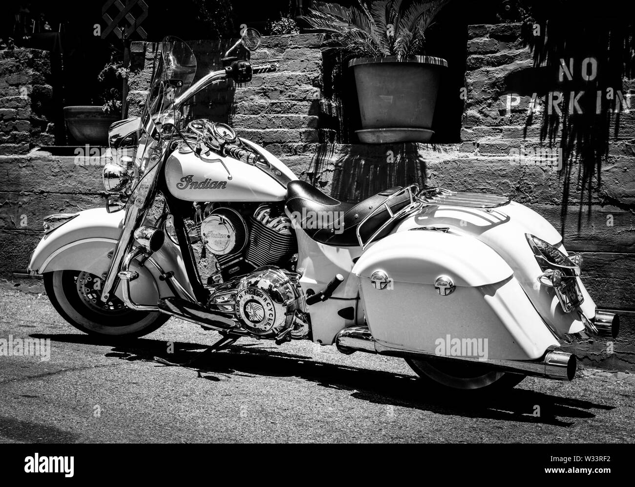 Un beau blanc Indian Motorcycle stationné dans une zone de stationnement interdit à proximité d'un mur de briques avec jardin dans le sud-ouest de l'USA, Banque D'Images