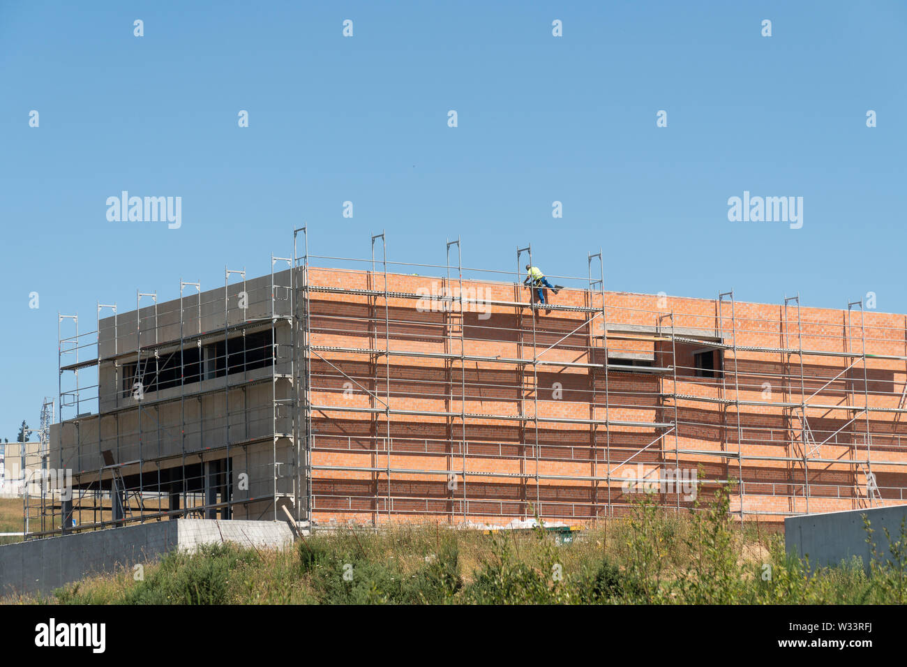 La construction de site avec des échafaudages et travailleur méconnaissable sauter à la toiture. Copy space Banque D'Images