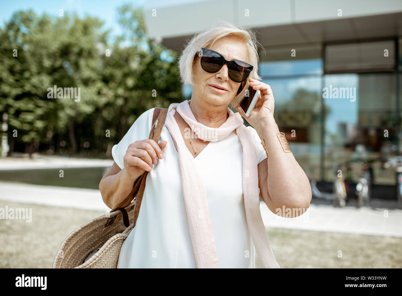 Senior woman élégant avec smartphone pendant la marche à l'extérieur de la ville. Concept de la vie de l'entreprise à la retraite Banque D'Images