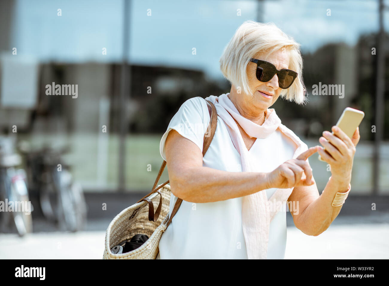 Senior woman using smartphone élégant tandis que la marche à l'extérieur de la ville. Concept de la vie de l'entreprise à la retraite Banque D'Images