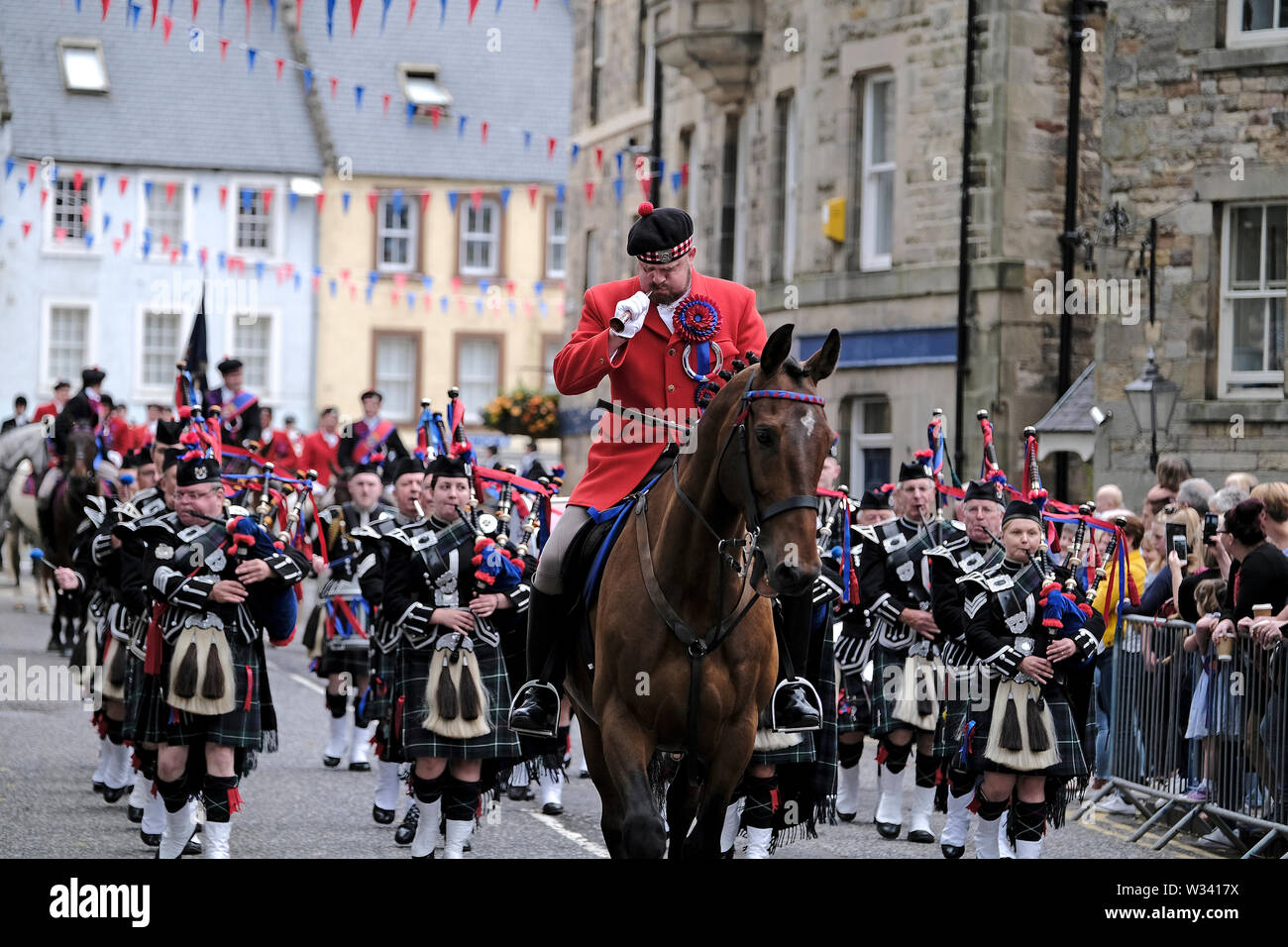 Jedburgh, Ecosse, Royaume-Uni. 12 juillet 2019. Jethart Callant Festival du Jour 2019 Jethart Callant Festival du Herald Robert Reid (en rose) conduit la chasse Jedburgh Pipe Band en avant de la Callant et sa gauche et droite de la menJethart Callant Festival du jour, un festival annuel, une partie de la saison de conduite commun écossais, le vendredi 12 juillet 2019, Jedburgh, Scottish Borders, Scotland, Royaume-Uni. Crédit : Rob Gray/Alamy Live News Banque D'Images