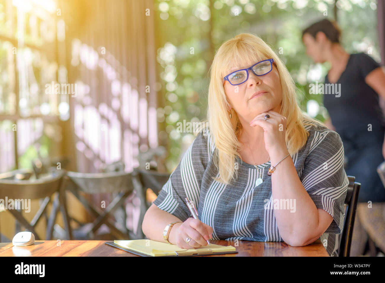 Portrait de belle taille plus femme d'âge moyen et de prendre des notes de son journal sur la terrasse de café. Âge moyen élégante dame posant avec Banque D'Images