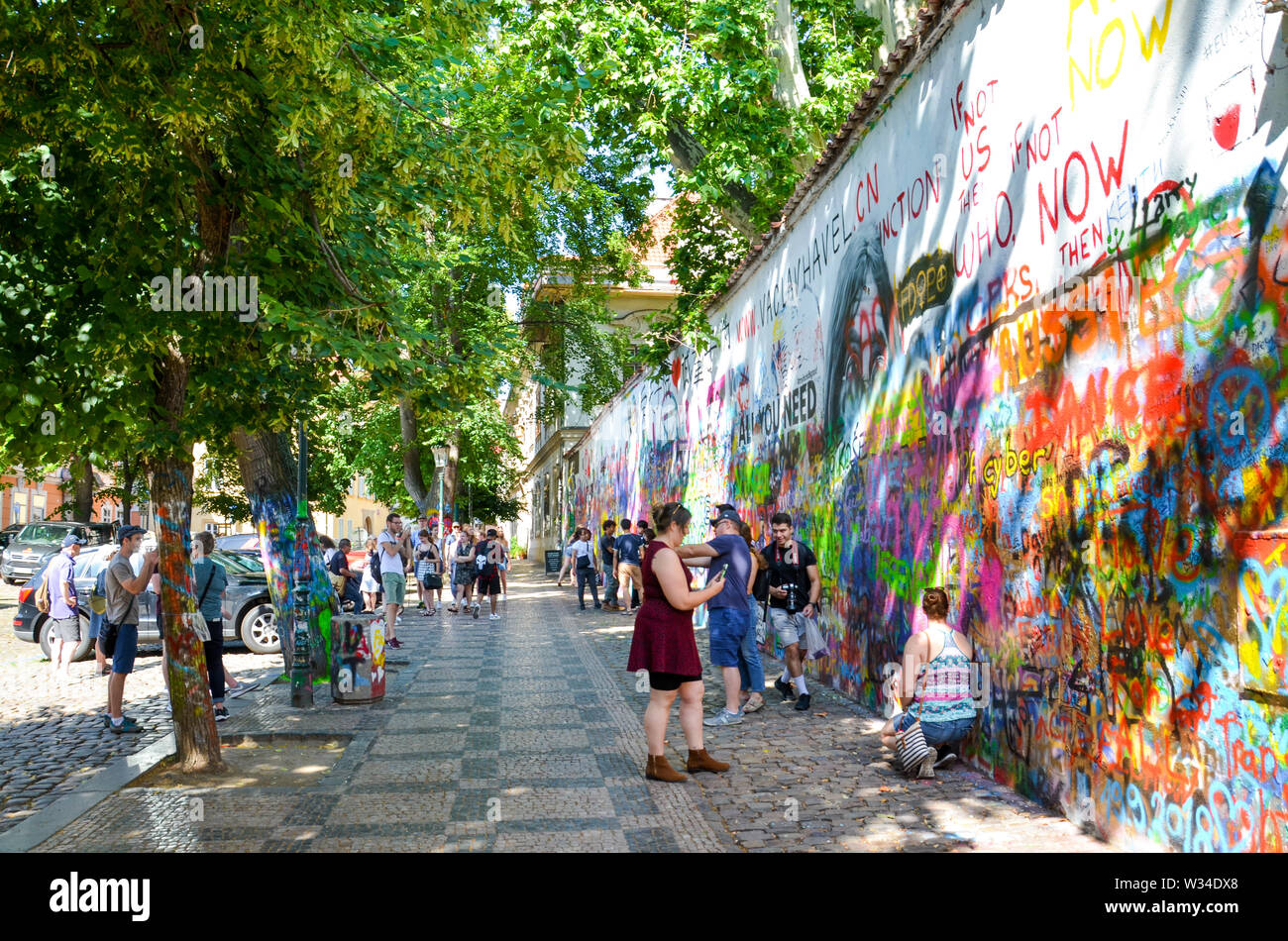 Prague, République tchèque - 27 juin 2019 : les touristes de prendre des photos en face de la célèbre John Lennon Wall dans le centre de la capitale tchèque. Mur de graffiti inspiré par le célèbre artiste. Lieu touristique populaire. Banque D'Images
