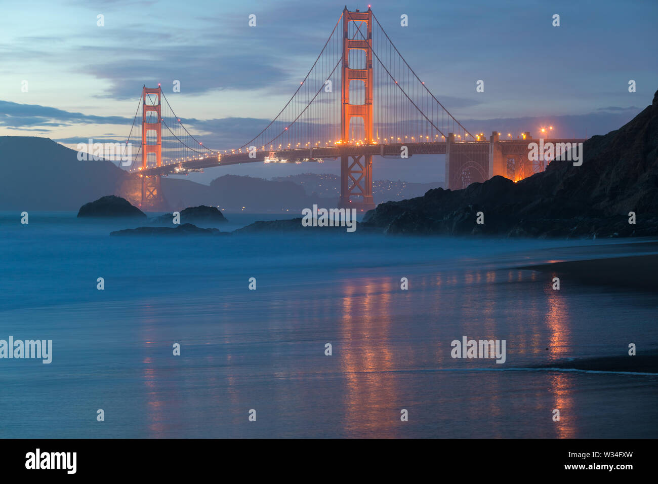 Vue panoramique classique du célèbre Golden Gate Bridge Pittoresque Baker Beach dans une belle lumière dorée le soir sur un coucher de soleil avec ciel bleu et nuage Banque D'Images