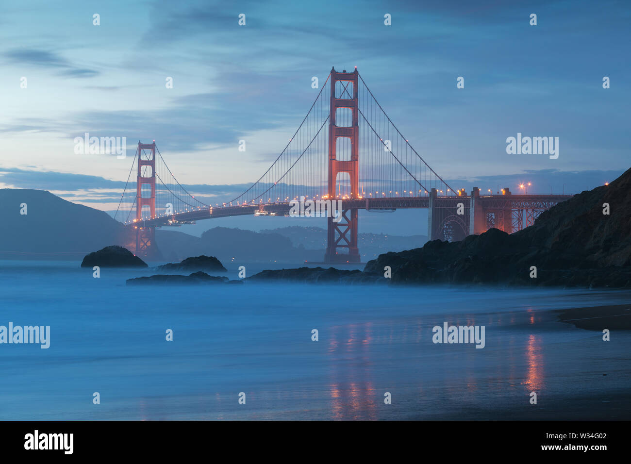 Vue panoramique classique du célèbre Golden Gate Bridge Pittoresque Baker Beach dans une belle lumière dorée le soir sur un coucher de soleil avec ciel bleu et nuage Banque D'Images