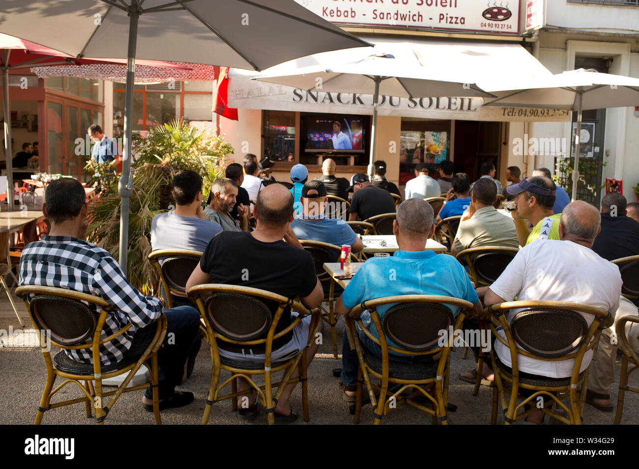 La France. Arles. 2019. Un groupe d'hommes assis regarder un match de football à la télévision à un café en plein air Banque D'Images
