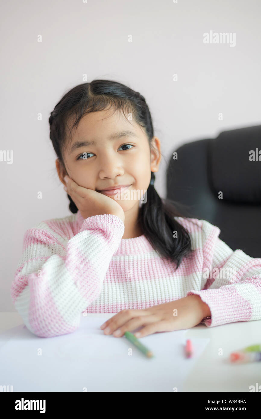 Petit portrait Asian girl assis sur le menton et sourire avec bonheur la pensée quelque chose de rêveur métaphore jour concept sélectionner focus faible profondeur de f Banque D'Images