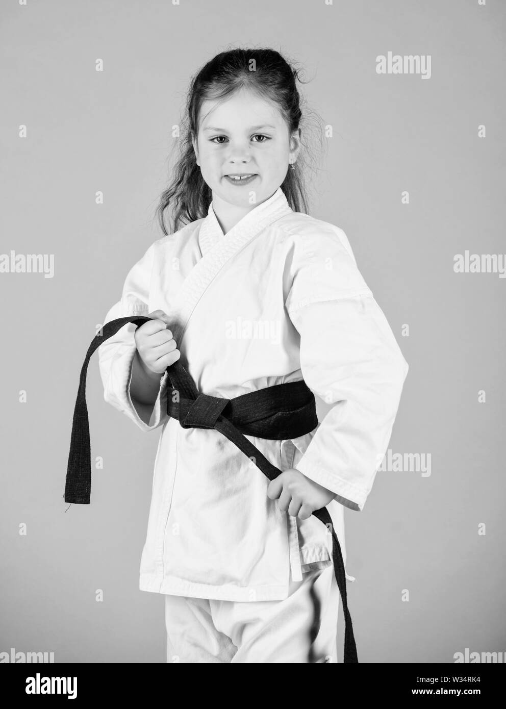 Le sport et l'activité. Kid forte et confiante. Petit enfant fille en kimono blanc avec ceinture. Karate fighter prêt à combattre. Karate sport concept. Compétences d'auto-défense. Le karaté donne un sentiment de confiance. Banque D'Images