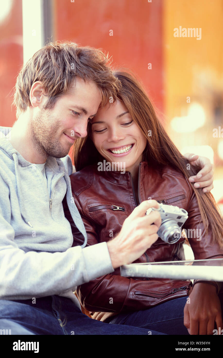 Happy young couple looking at photos sur l'appareil-photo. Beaux jeunes amoureux s'amuser ensemble à l'extérieur de regarder des photos sur retro vintage appareil photo. Couple Interracial, Asian Woman, man. Banque D'Images