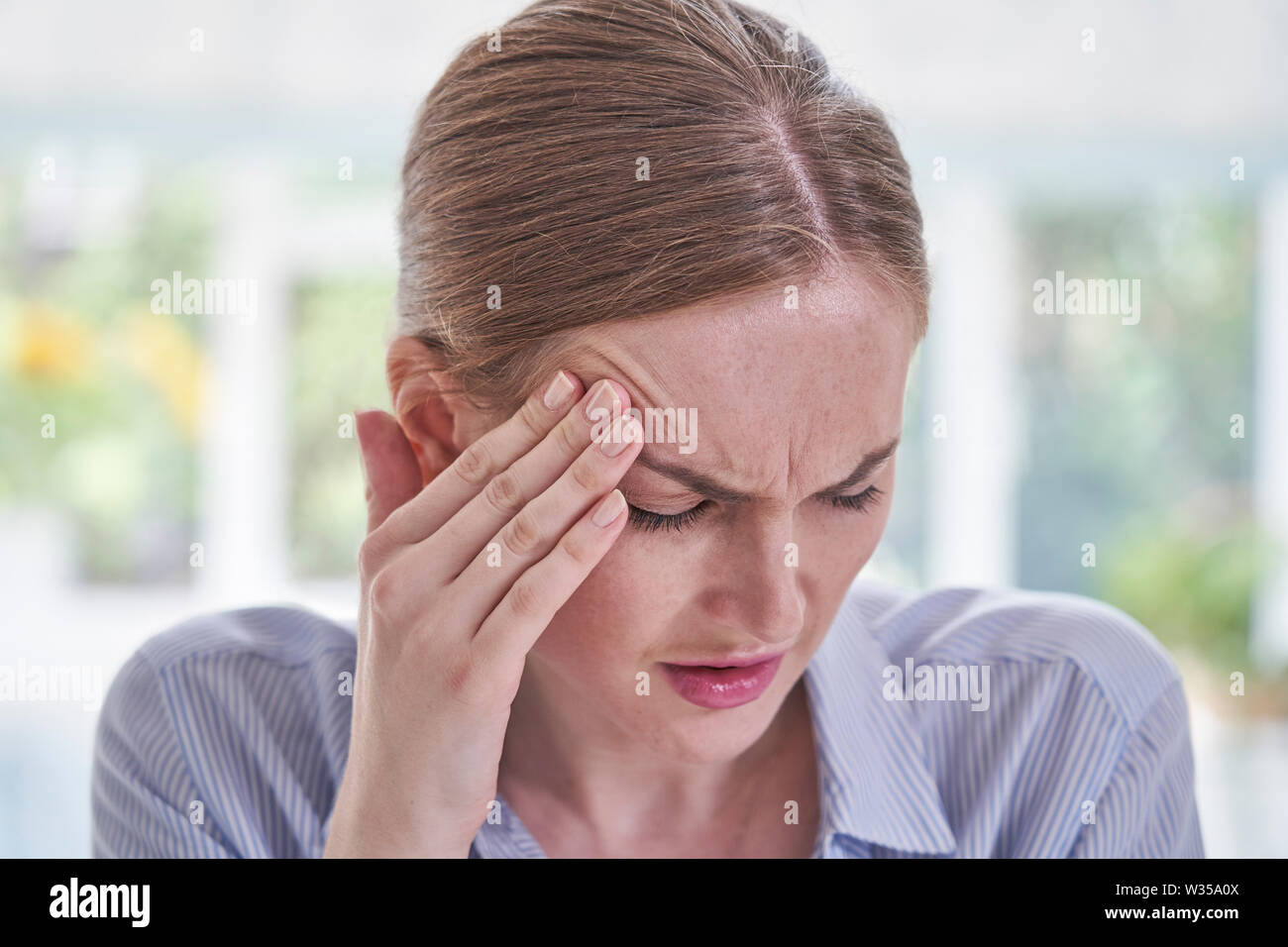 Femme a souligné la souffrance avec maux de tête In Office Banque D'Images