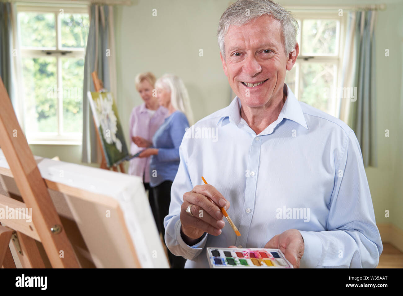 Portrait of Senior Man assistant à classe de peinture avec l'enseignant en arrière-plan Banque D'Images