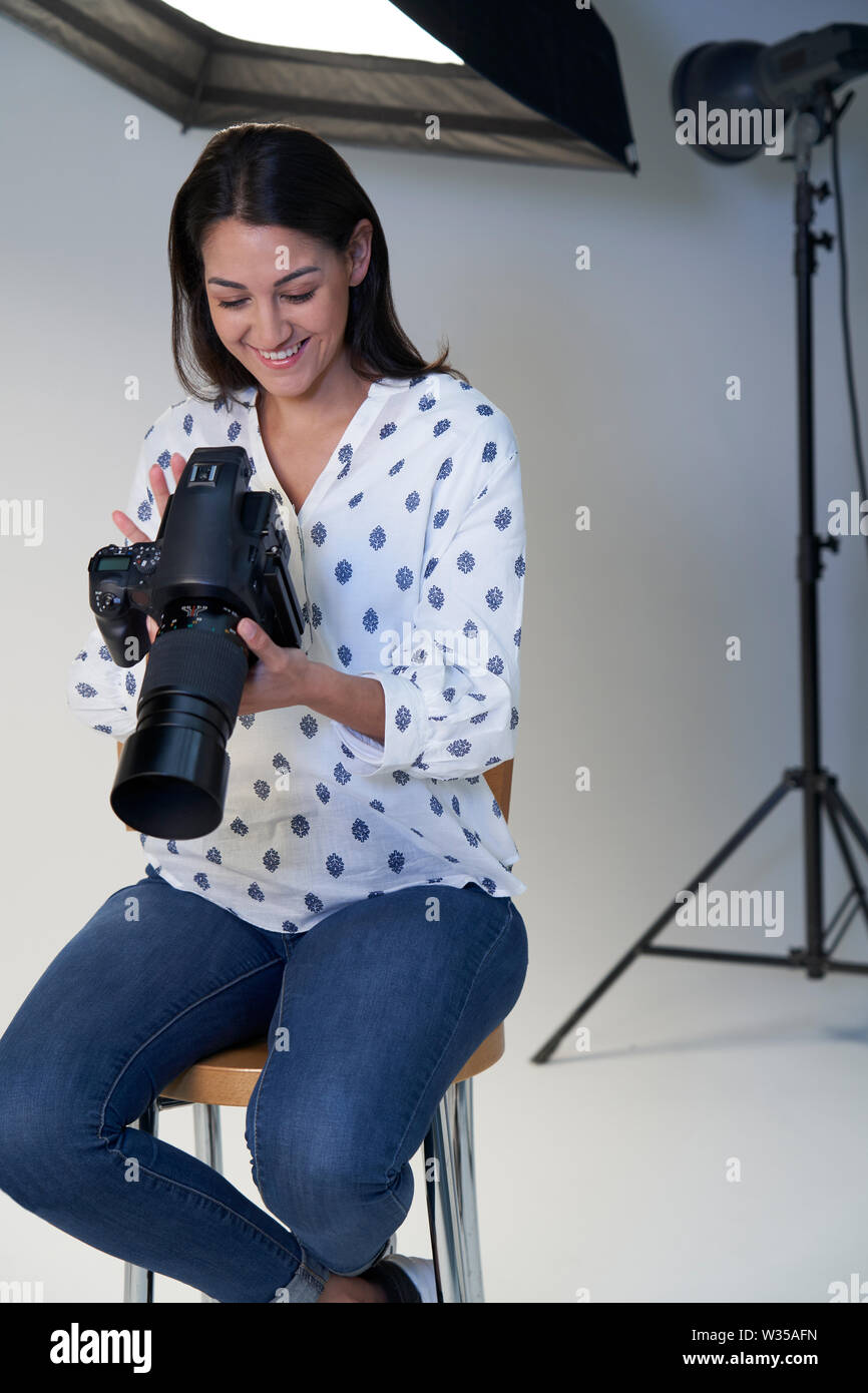 Femme photographe en studio pour la séance photo avec l'appareil photo et l'équipement d'éclairage Banque D'Images