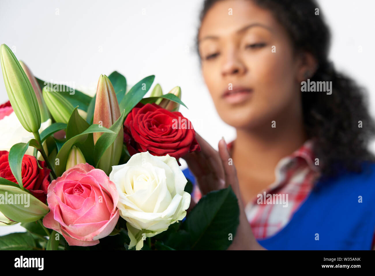 Studio Shot of Female Florist Organisation Bouquet de roses et Lys Against White Background Banque D'Images