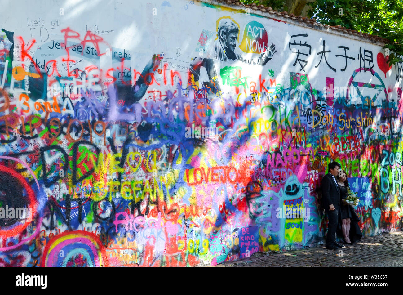 Prague, République tchèque - 27 juin 2019 : pendant la séance photo de mariage en face du célèbre John Lennon Wall en capitale tchèque. Mur de graffiti inspiré par le célèbre artiste. Lieu touristique populaire. Banque D'Images