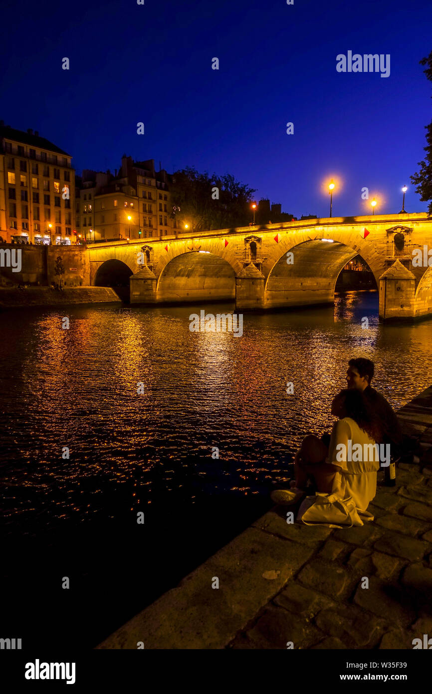 Jeune couple au pont Marie illuminé la nuit Ile Saint Louis, au bord de la Seine, Paris, France. Banque D'Images