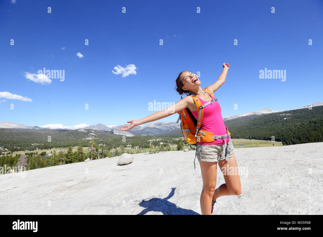 Bonne randonnée femme dansant dans paysage de montagne. Les jeunes adultes asiatiques faire drôle liberté posent sur le haut de la Poule Dome à Yosemite National Park, California, USA. Banque D'Images