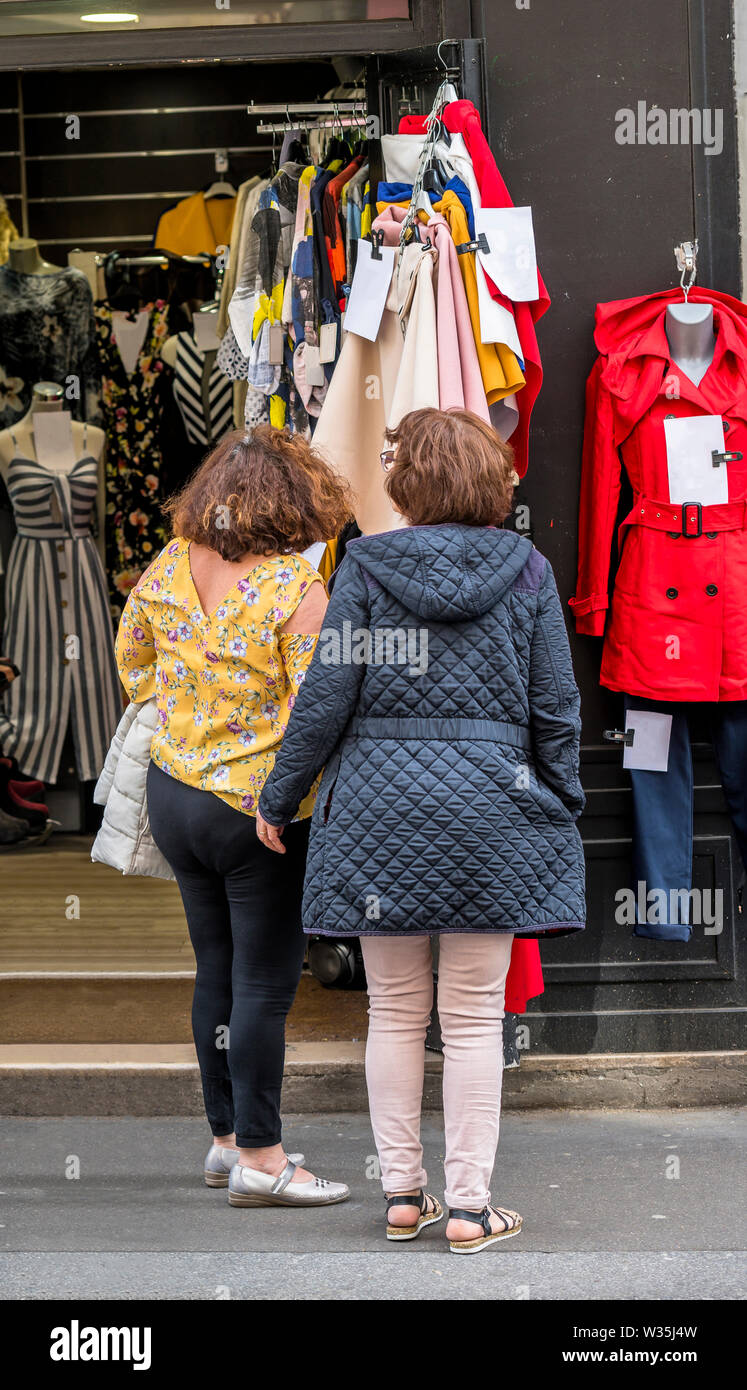 Deux femmes attirés par l'aubaine d'habillement pour femmes dans la boutique s'est arrêté pour se familiariser avec les prix et choisir un style à la mode d'e Banque D'Images