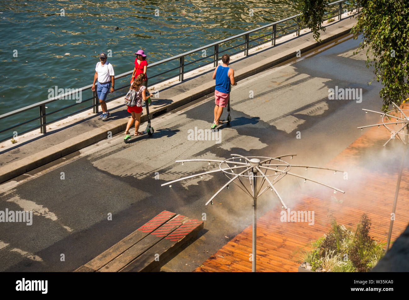 Les piétons circulant le long de la Seine soulagé d'aspersion d'eau, pendant la vague de chaleur. Paris, France. Banque D'Images