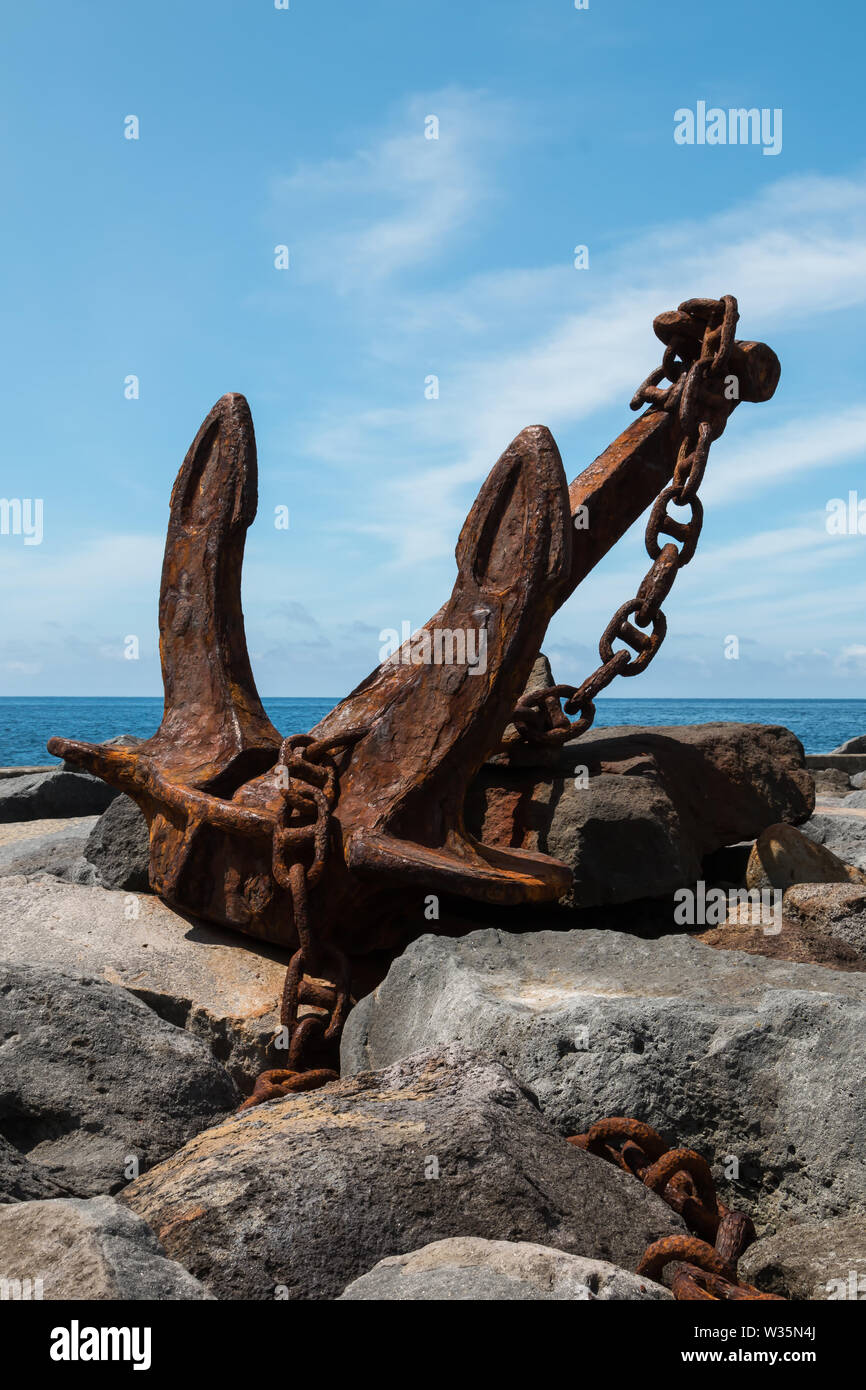 Vieille ancre rouillée avec une chaîne, exposés dans la zone du port sur les rochers sur la côte de l'océan Atlantique. Ciel bleu avec des nuages blancs. Povoacao, Sao Banque D'Images Vieille ancre rouillée avec une chaîne, exposés dans la zone du port sur les rochers sur la côte de l'océan Atlantique. Ciel bleu avec des nuages blancs. Povoacao, Sao Banque D'Images
