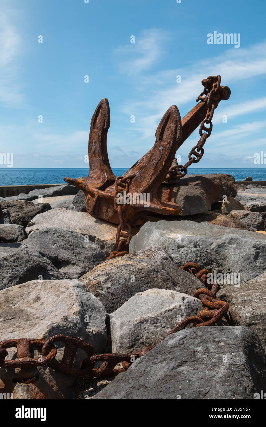 Vieille ancre rouillée avec une chaîne, exposés dans la zone du port sur les rochers sur la côte de l'océan Atlantique. Ciel bleu avec des nuages blancs. Povoacao, Sao Banque D'Images Vieille ancre rouillée avec une chaîne, exposés dans la zone du port sur les rochers sur la côte de l'océan Atlantique. Ciel bleu avec des nuages blancs. Povoacao, Sao Banque D'Images