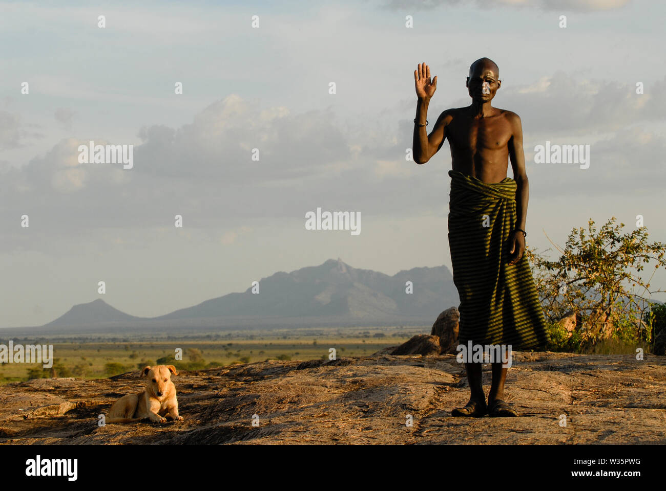 L'Ouganda, le Karamoja, tribu Karimojong, guerrier en face de paysage de montagne Banque D'Images