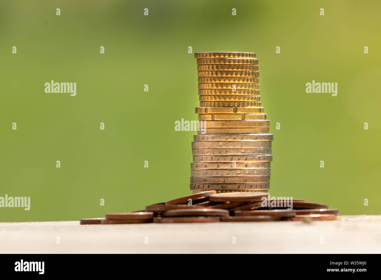 Pièce de monnaie sur la table en bois en face de l'arrière-plan flou vert. Il y a de la lumière flare sur la droite. Pièces de monnaie empilés sur la table. Banque D'Images