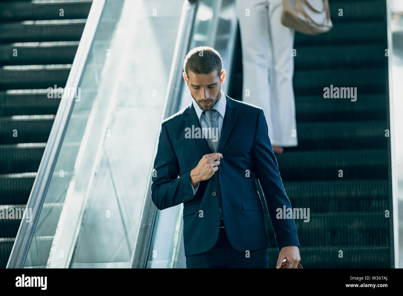 Caucasian businessman using escalators in modern office Banque D'Images