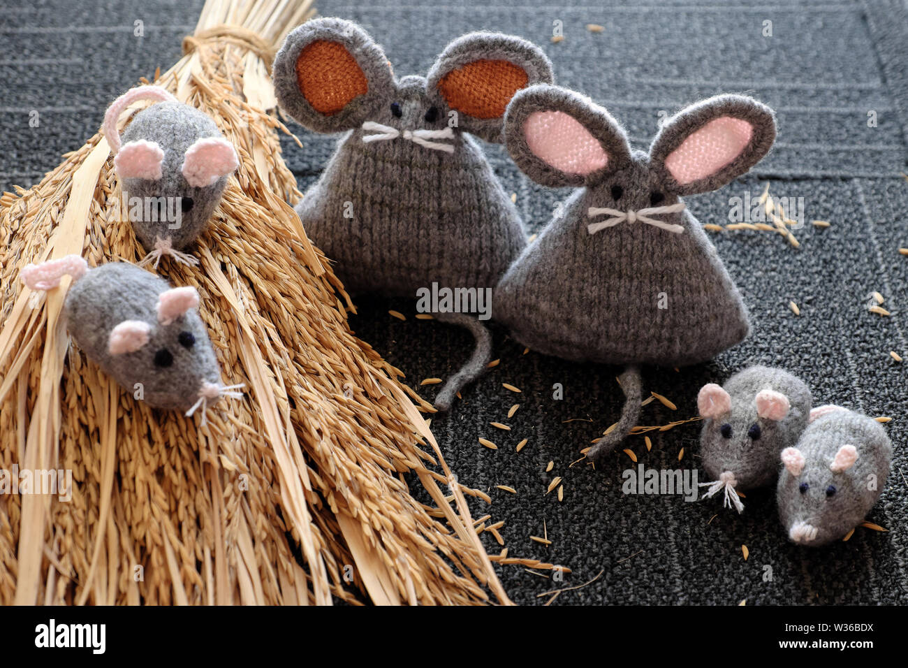 Groupe de tricot fait main gris souris sur la gerbe de plants de riz, avec fond noir, rat d'artisanat à partir de fils si mignon et gentil, significatifs pour cadeau ou Banque D'Images