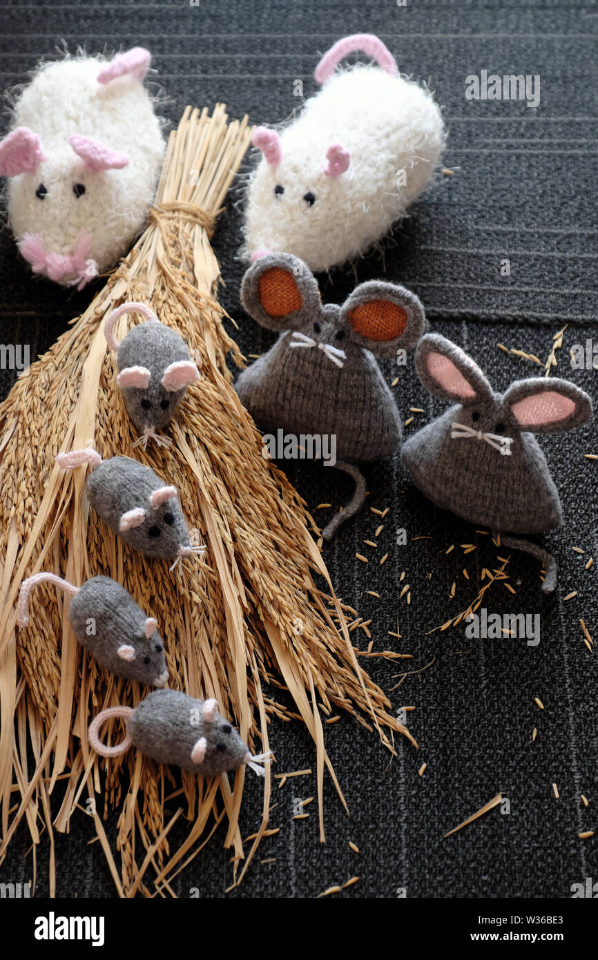 Groupe de tricot fait main gris souris sur la gerbe de plants de riz, avec fond noir, rat d'artisanat à partir de fils si mignon et gentil, significatifs pour cadeau ou Banque D'Images