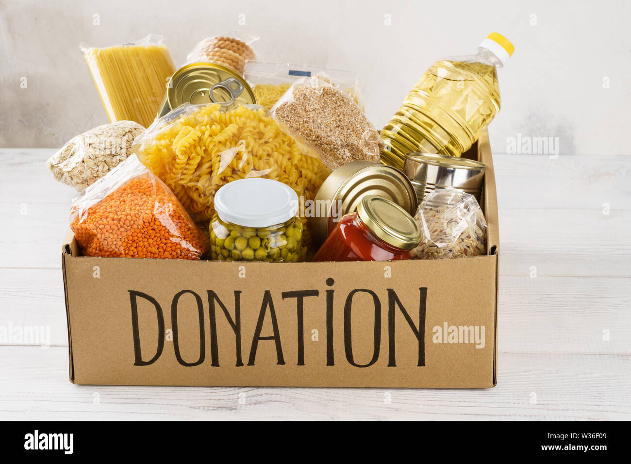 Donation box avec divers aliments. Ouvrir boîte en carton avec de l'huile, de la nourriture en conserve, céréales et pâtes alimentaires. Banque D'Images