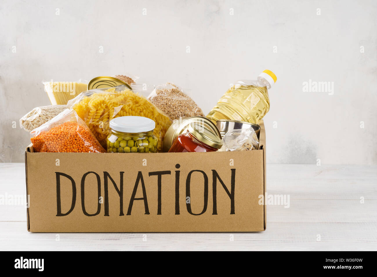 Donation box avec divers aliments. Ouvrir boîte en carton avec de l'huile, de la nourriture en conserve, céréales et pâtes alimentaires. Copier l'espace. Banque D'Images