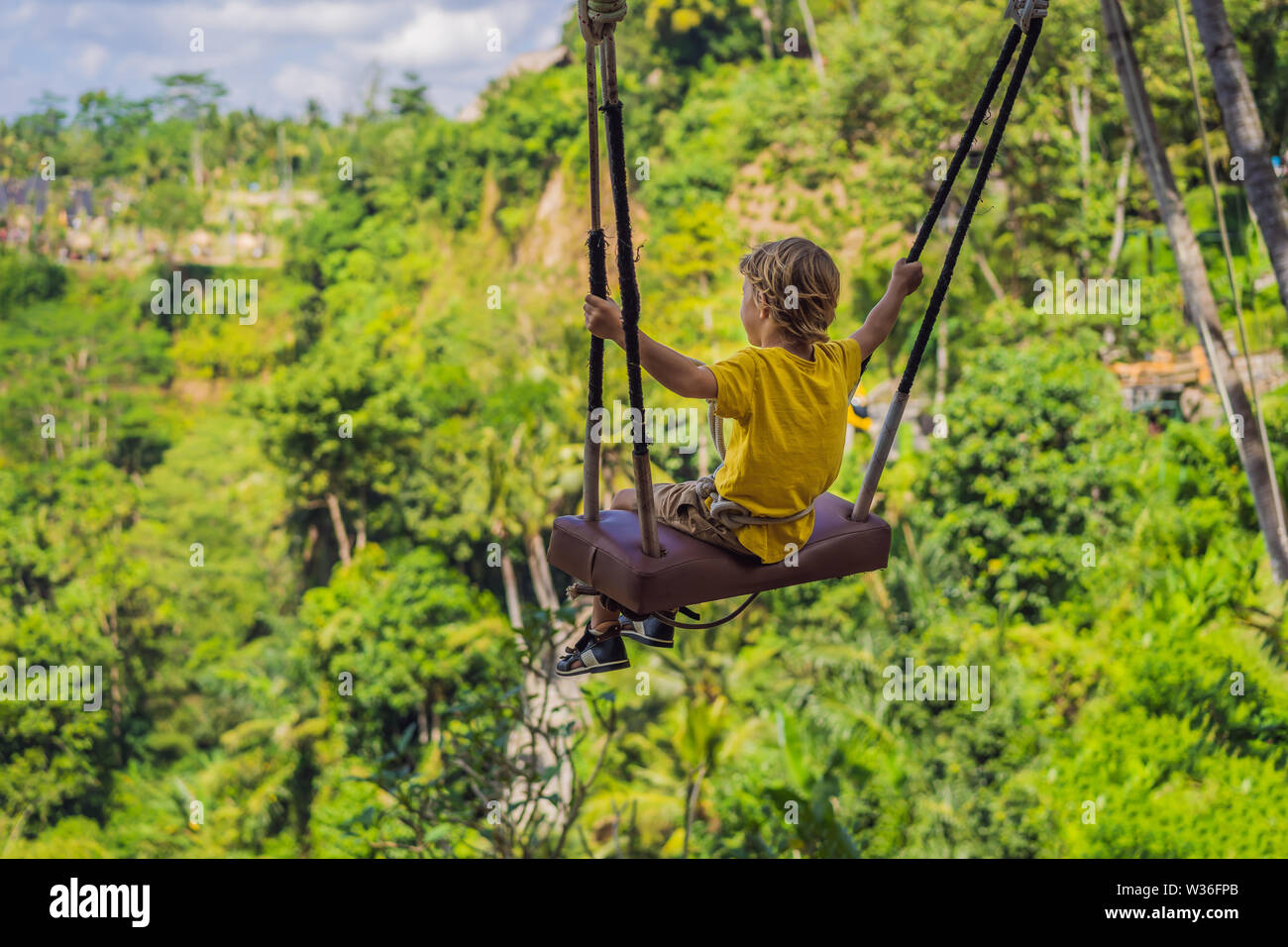 Jeune garçon se balançant dans la jungle pour les forêts tropicales de  l'île de Bali, Indonésie. Swing sous les tropiques. Balançoires - tendance  de Bali. Concept de voyager avec des enfants. Ce