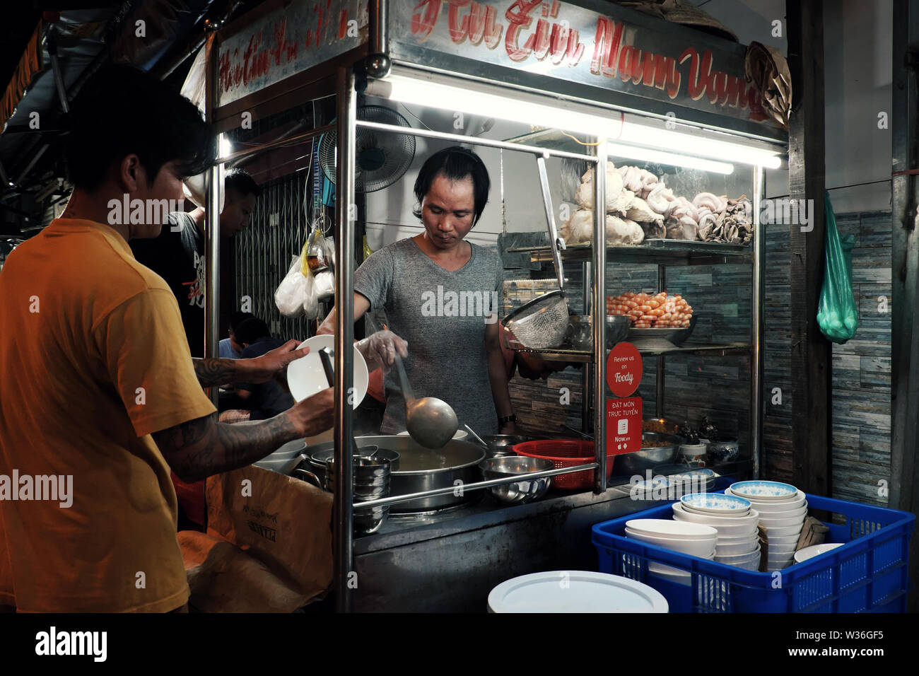 Homme vietnamien soupe aux nouilles cook sur la voiturette à l'alimentation de rue de nuit, chaud bol de nouilles avec de la viande, les crevettes si délicieux à manger, Vietnam Banque D'Images