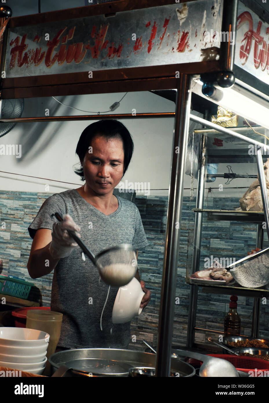 Homme vietnamien soupe aux nouilles cook sur la voiturette à l'alimentation de rue de nuit, chaud bol de nouilles avec de la viande, les crevettes si délicieux à manger, Vietnam Banque D'Images