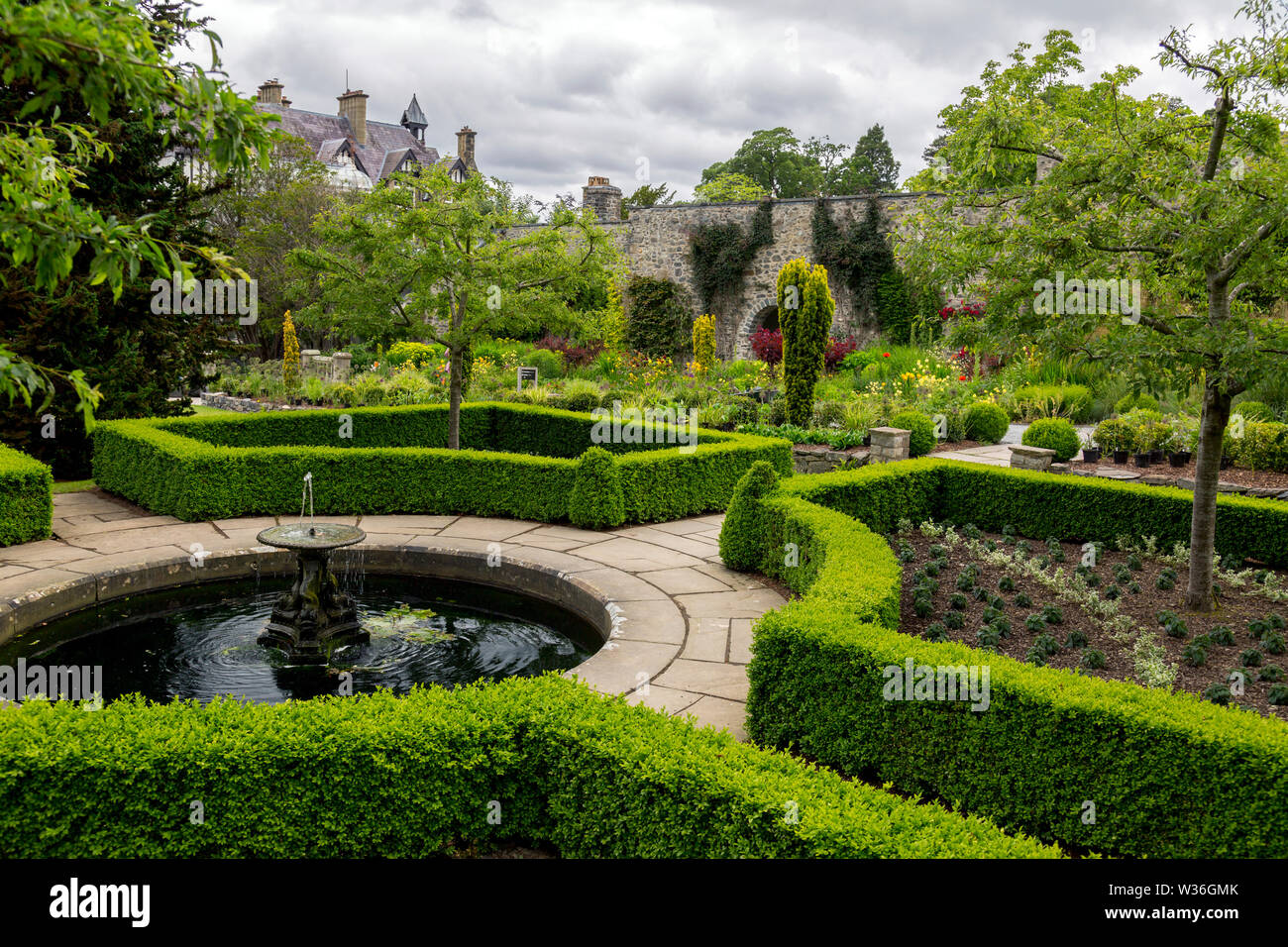 Fort bien clipsé haies entourant une petite piscine avec fontaine à jardins Bodnant, Conwy, Pays de Galles, Royaume-Uni Banque D'Images