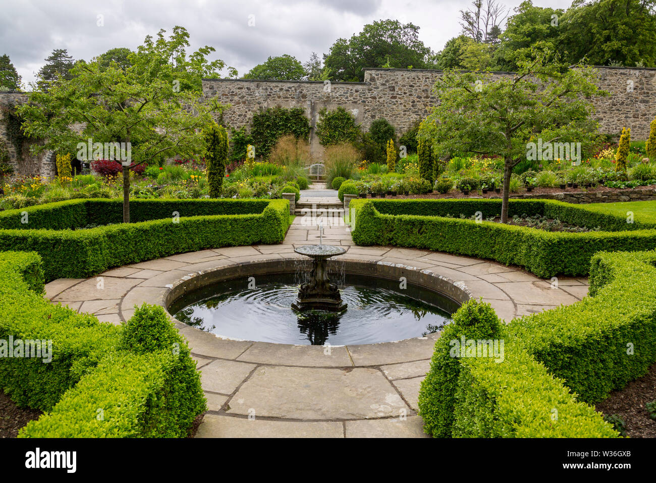 Fort bien clipsé haies entourant une petite piscine avec fontaine à jardins Bodnant, Conwy, Pays de Galles, Royaume-Uni Banque D'Images