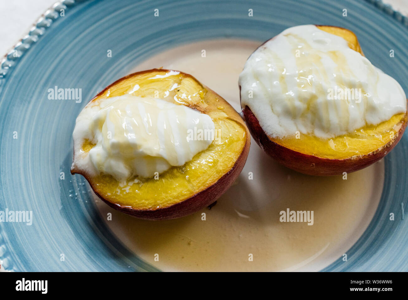 Pêches au four avec du yaourt grec et le miel / les nectarines. Dessert bio. Banque D'Images