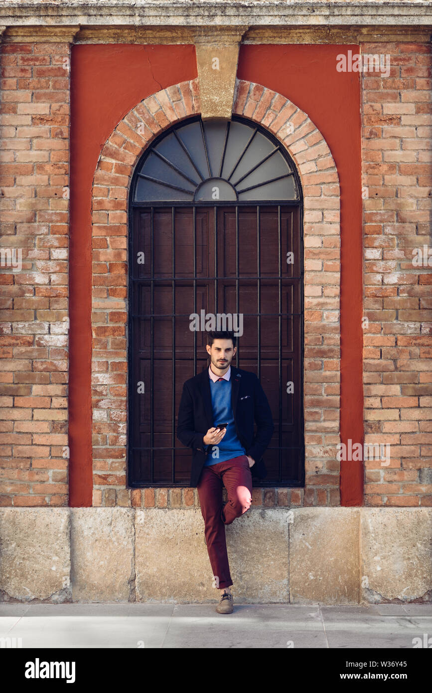 Homme dans la rue en soirée avec le smartphone à la main. Banque D'Images