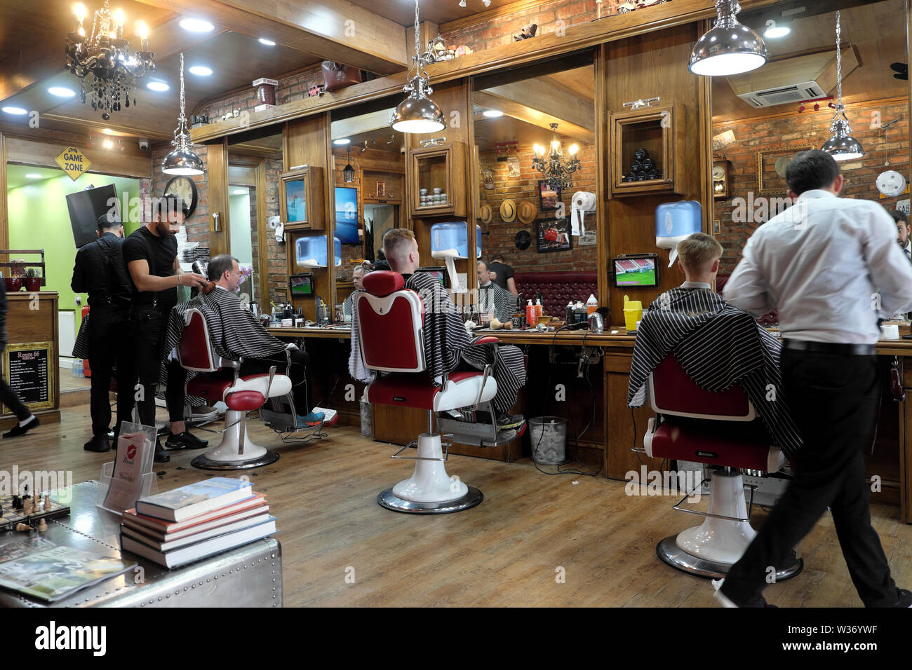 Coiffeur coupant les cheveux de l'homme et les hommes assis dans des chaises de barbiers À l'intérieur du salon de coiffure de la route 66 à Wellfield Road Cardiff PAYS DE GALLES ROYAUME-UNI KATHY DEWITT Banque D'Images