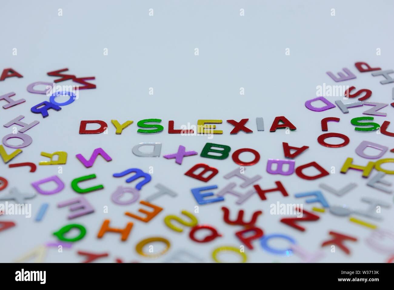 La dyslexie, énoncé dans les confettis lettres alphabet, entouré par une mer de lettres aléatoires, sur un fond blanc. Concept créatif : incapacité de lecture Banque D'Images