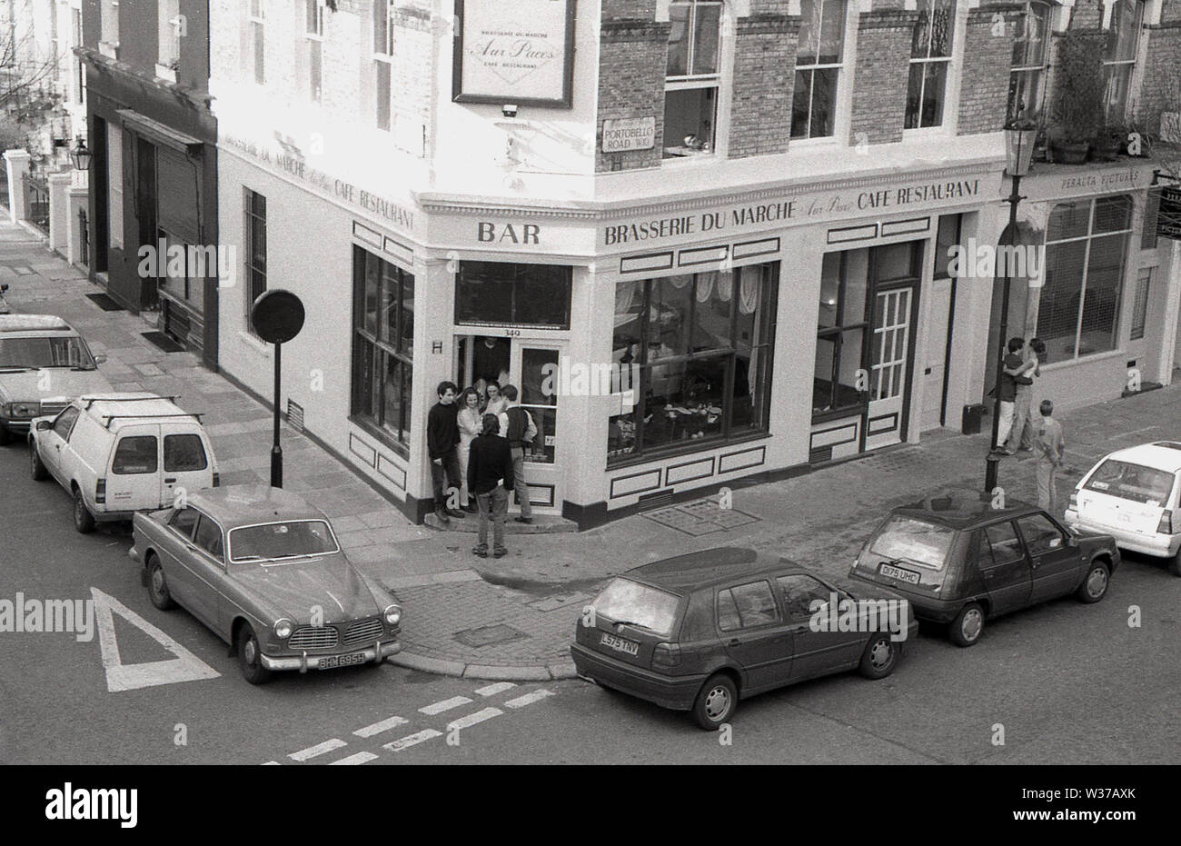 Années 1970, historique, vue d'en haut, d'une fenêtre de voitures garées dans une rue et des gens à l'entrée de la Brasserie du Marche, un café restaurant de style français au coin de la célèbre Portobello Rd, à Notting Hill, West London, W10, Angleterre, ROYAUME-UNI. Banque D'Images
