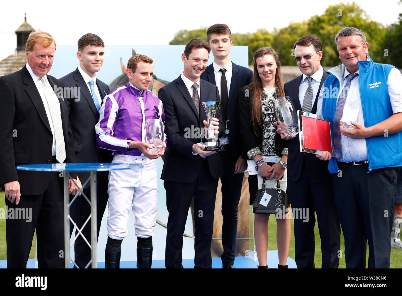 Jockey Ryan Moore (troisième à gauche), propriétaire Paul D Smith (centre) et formateur Aiden O'Brien (deuxième à droite) après la victoire dans la coupe Juillet Darley Stakes au cours de la troisième journée du Moet et Chandon Festival Juillet 2019 à Newmarket Racecourse. Banque D'Images