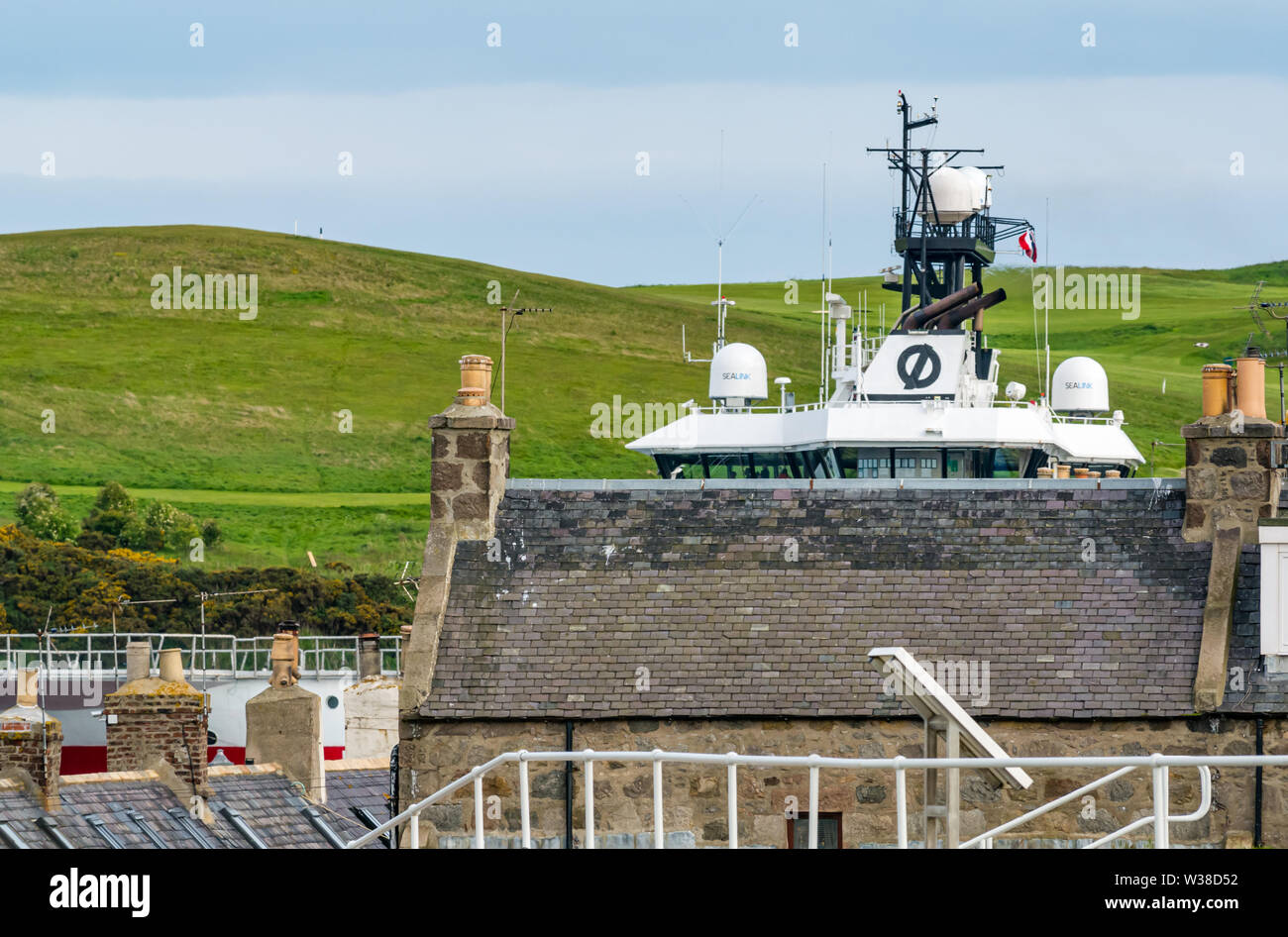 Bateau quittant le port d'Aberdeen, surplombant les toits de chalets de Footdee, en Écosse, au Royaume-Uni Banque D'Images