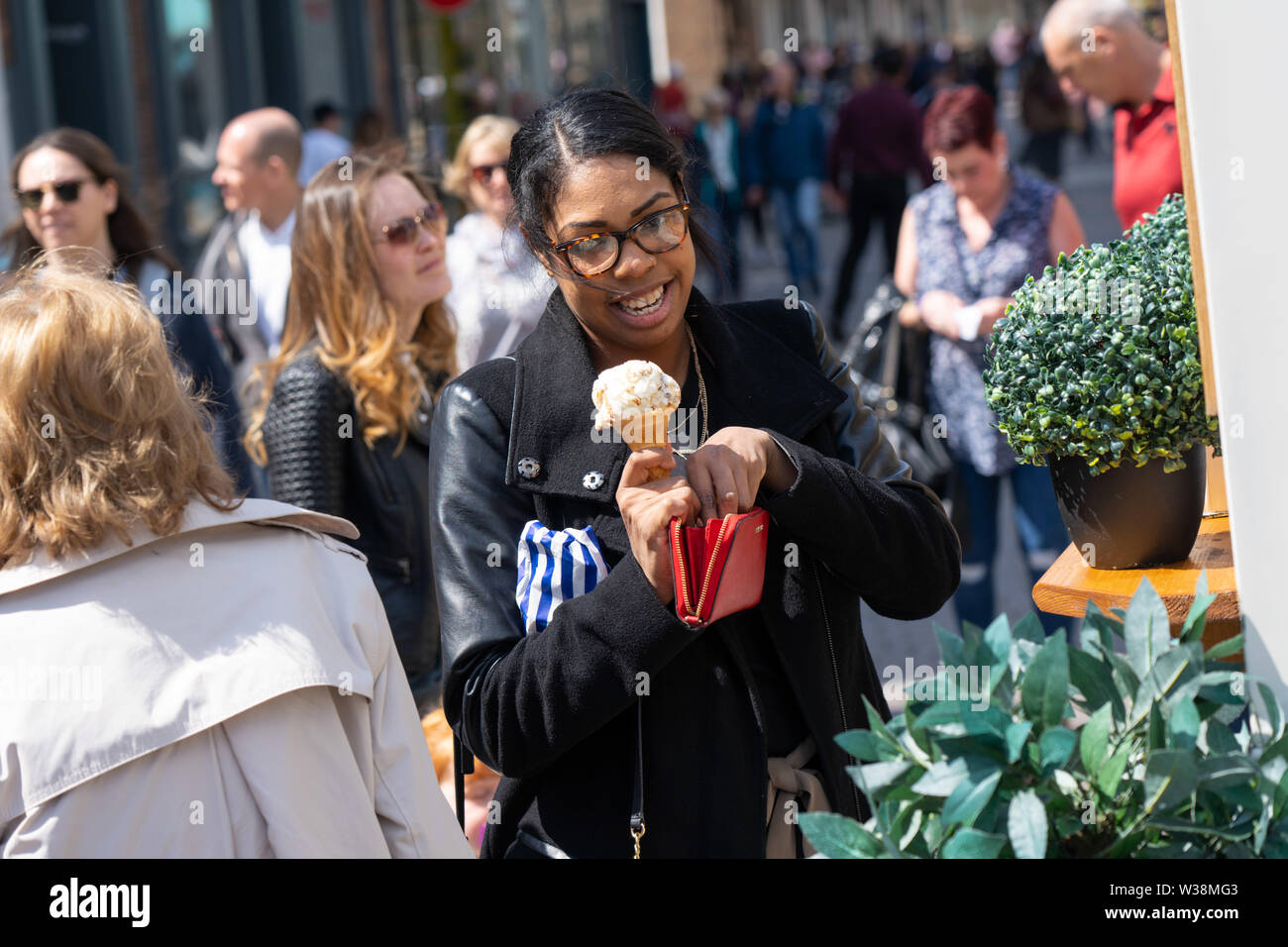 Femme tenant une crème glacée fraîchement achetée dans le centre de York, North Yorkshire, Angleterre, Royaume-Uni. Banque D'Images