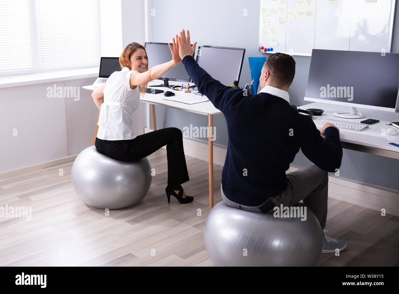 Businessman And Businesswoman Sitting on Fitness Ball offrant un rapport  cinq In Office Photo Stock - Alamy