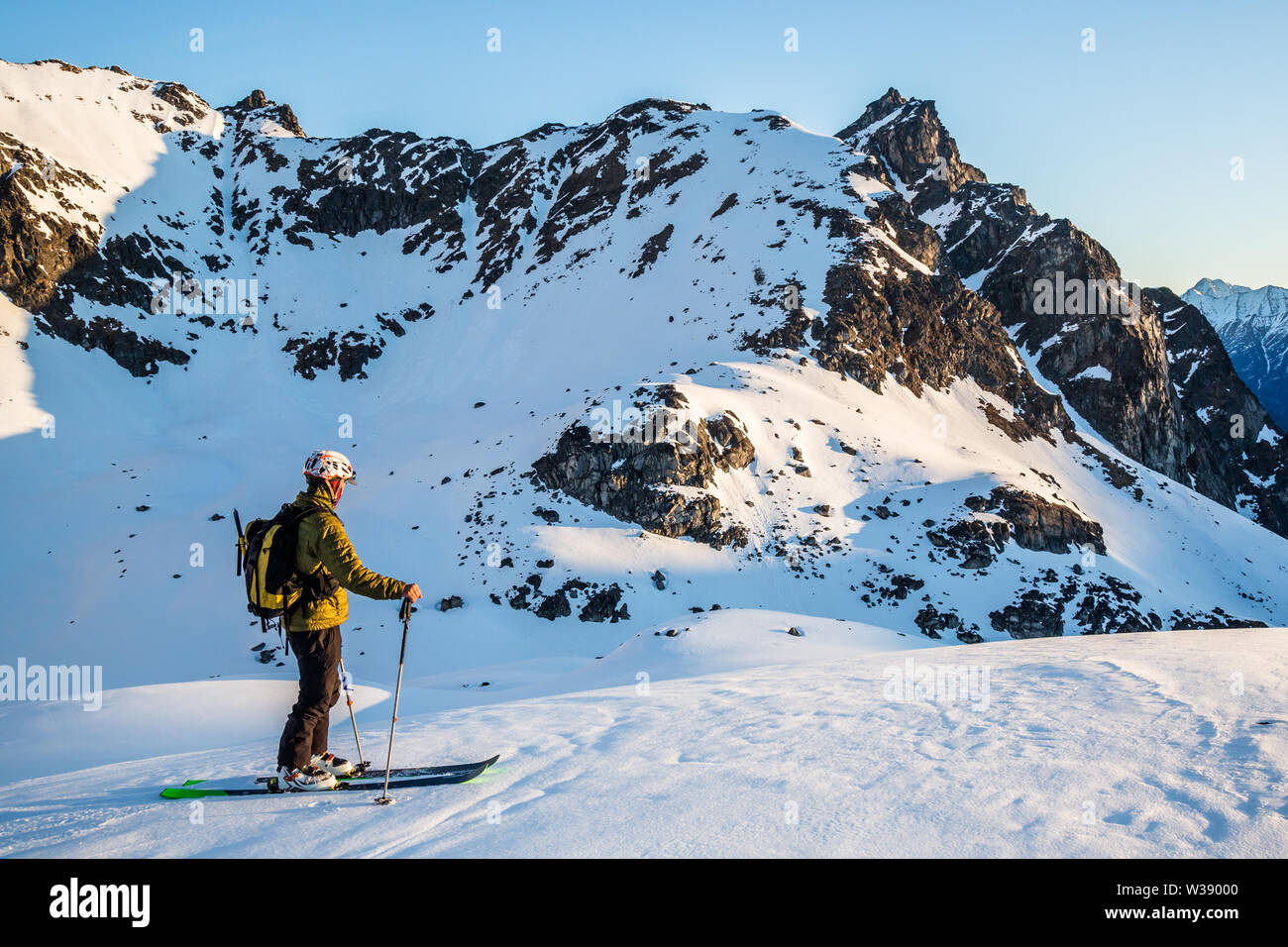 Un skieur hors-piste dans les montagnes de Talkeetna Alaska s'arrête pour profiter de la première lumière de l'un des premiers lever du soleil au printemps. Banque D'Images
