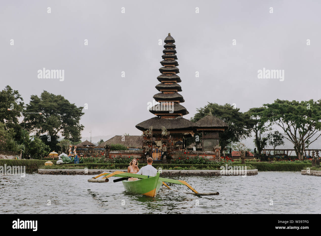 Jeune beau couple pagayer sur un bateau en bois à Pura Ulun Danu Bratan, Bali - Touristes explorer Bali Banque D'Images