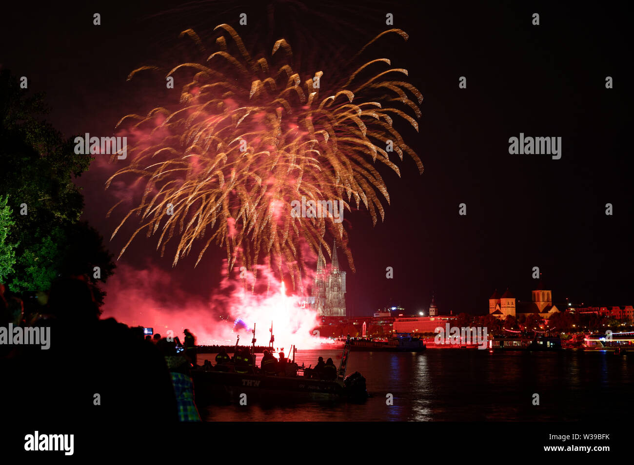 Cologne, Allemagne. Le 13 juillet, 2019. Les spectateurs suivent le grand feu d'artifice sur les rives du Rhin à la musique de Jacques Offenbach dans le cadre de la "Cologne". Credit : Henning Kaiser/dpa/Alamy Live News Banque D'Images