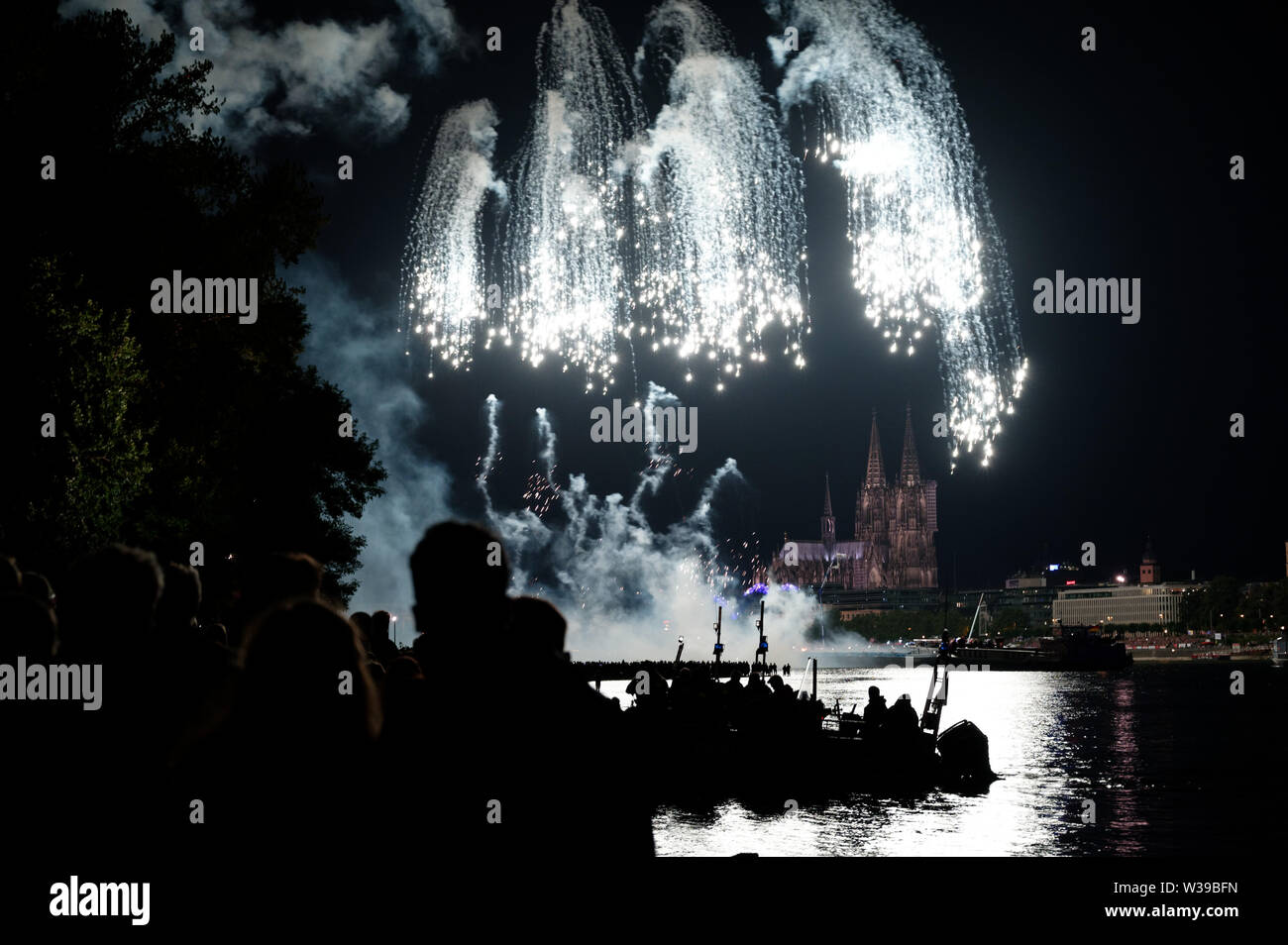 Cologne, Allemagne. Le 13 juillet, 2019. Les spectateurs suivent le grand feu d'artifice sur les rives du Rhin à la musique de Jacques Offenbach dans le cadre de la "Cologne". Credit : Henning Kaiser/dpa/Alamy Live News Banque D'Images