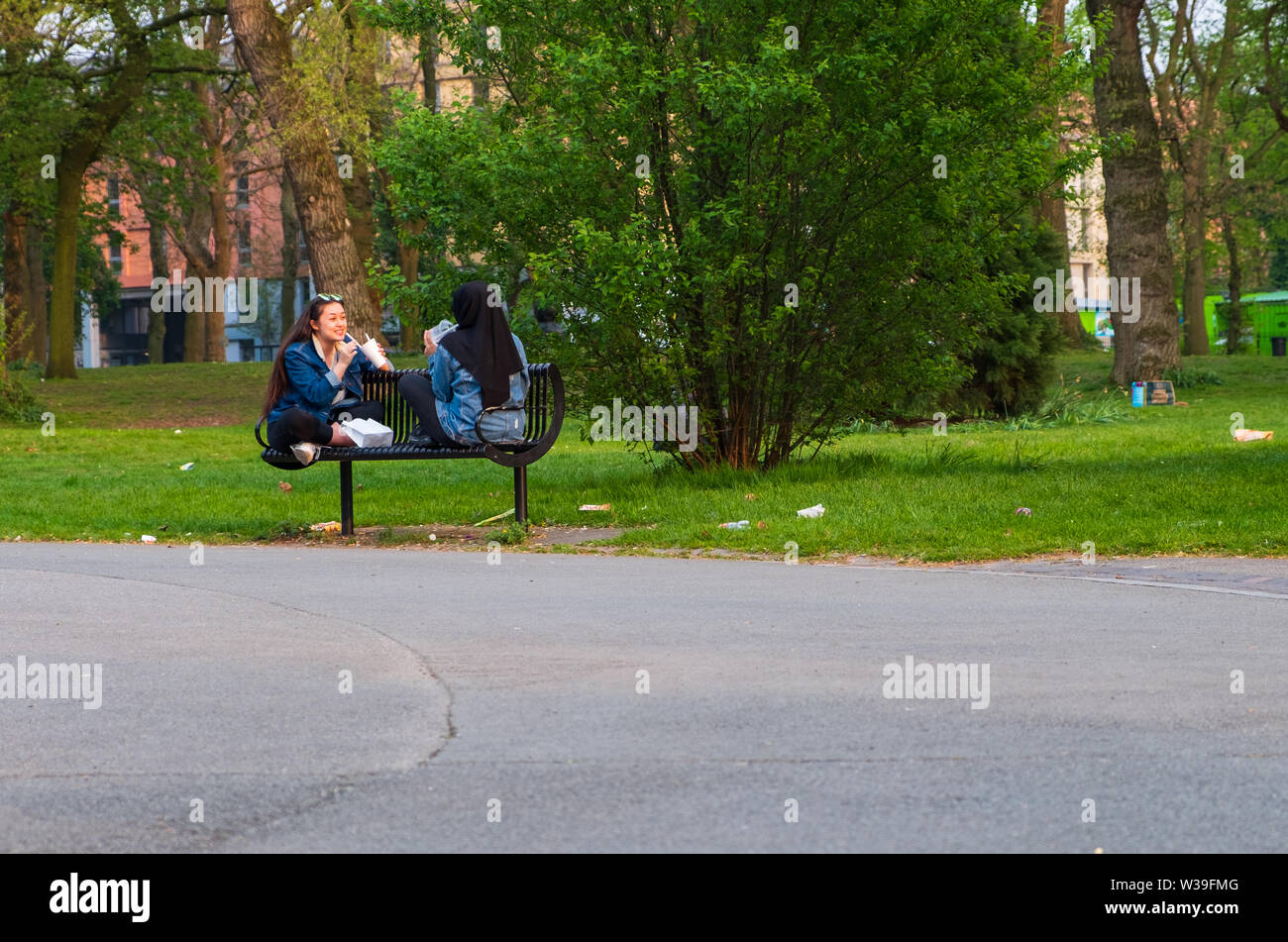 Manchester, Royaume-Uni - 22 Avril 2019 : deux femmes gaies sur un banc profitant de leurs boissons au Whitworth Park Banque D'Images